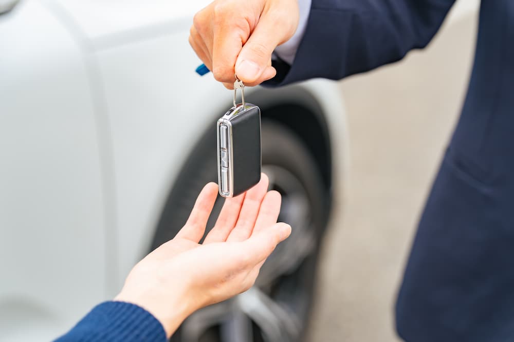 自動車のスマートキーを手渡す男性