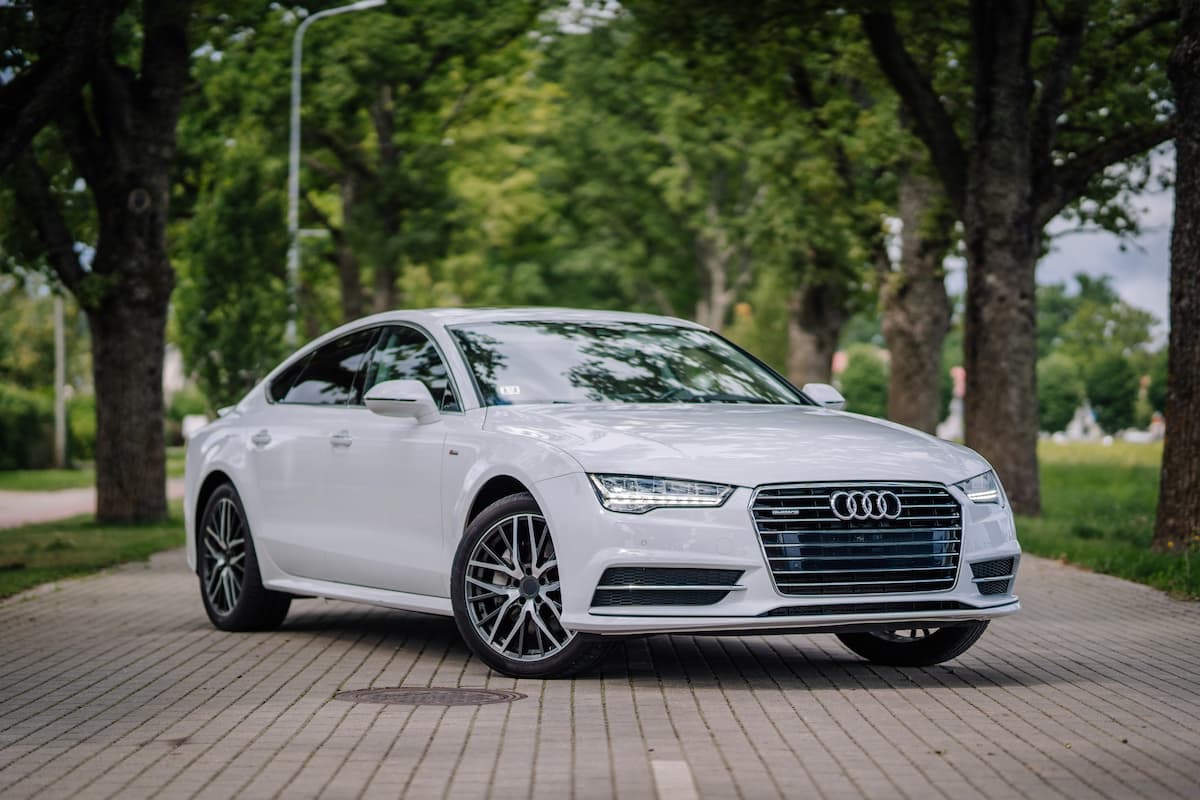 白いアウディセダンが並木道に停められている