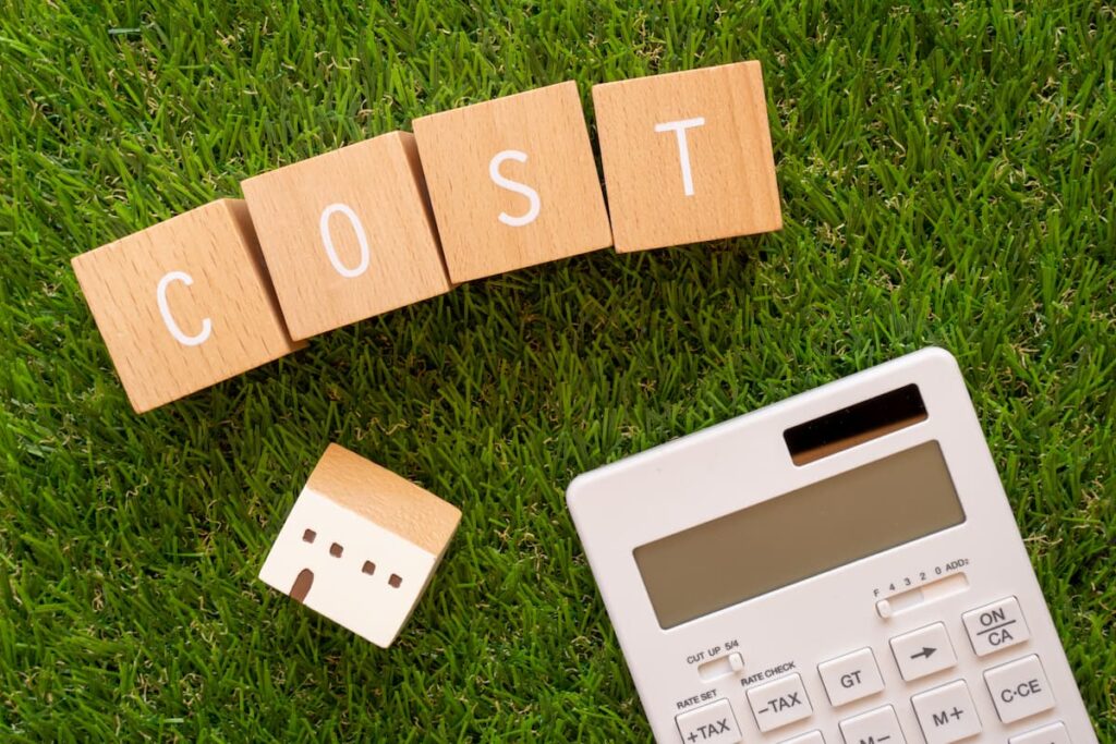 「COST」と書かれた積み木ブロックと家のおもちゃと電卓